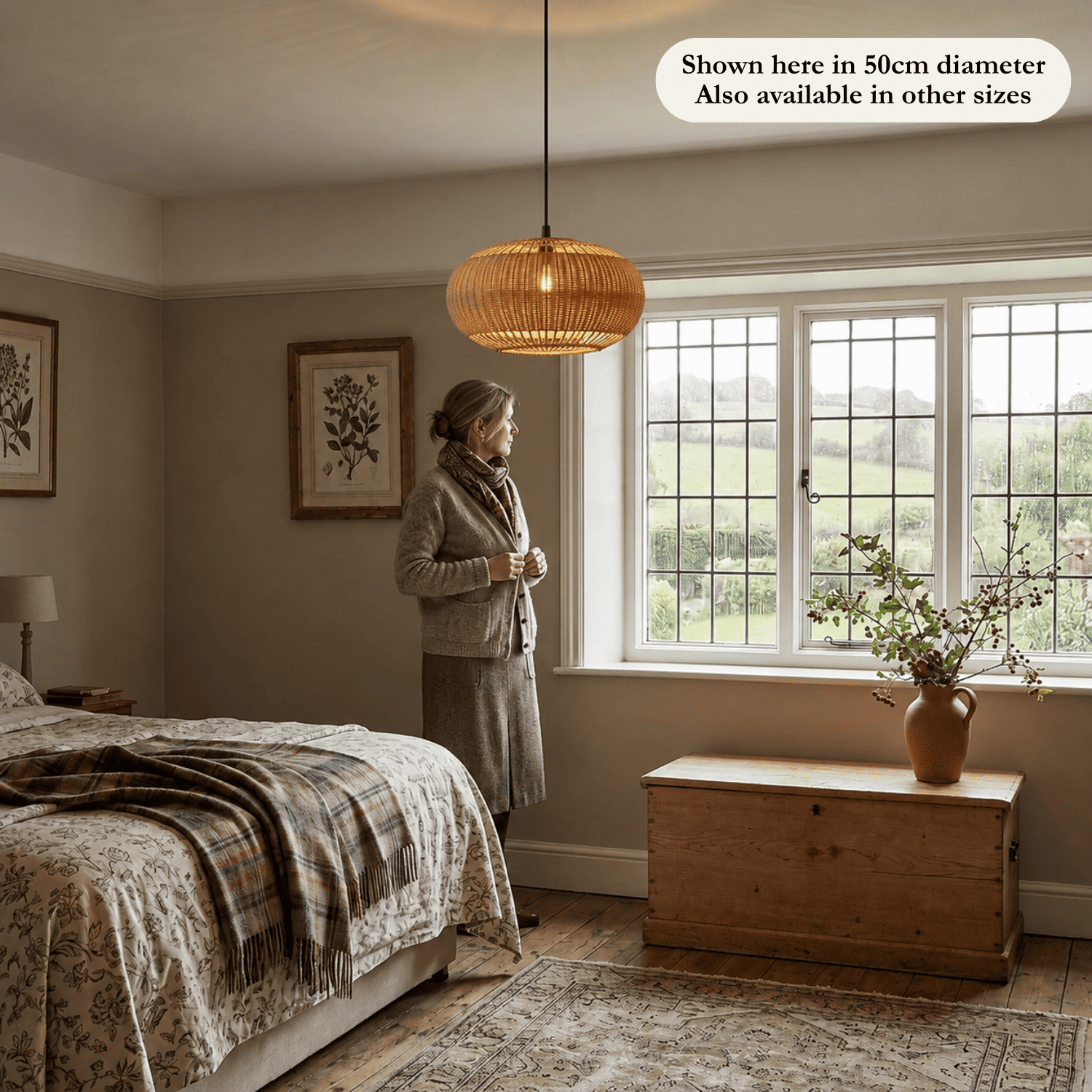 Isla wicker lampshade hanging in a cosy British bedroom with a woman standing next to the window