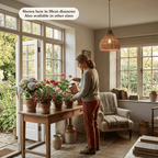 Woman watering potted plants on a table beneath the Maren wicker lampshade